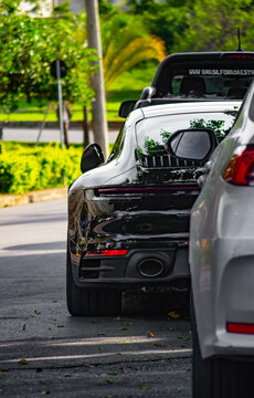 Black Porsche 911 parked between cars in open street - High Resolution Image