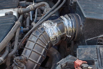 Air intake hose temporary repair with transparent duct tape. Air intake hose problems. Damaged rubber tube, hole in hose pipe. Broken air intake hose, needs to replacement. Patching an air intake hose