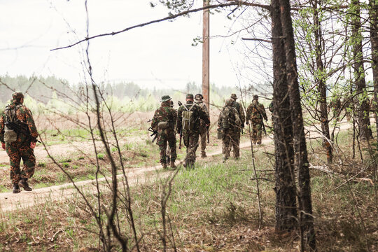 Group of russian soldiers in military camouflage uniform with weapon move in forest road outdoors. Males russia warriors armed on mission. Military and army on war concept. Copy ad text space