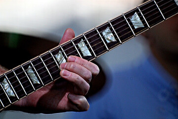 Guitarist's fingers playing on guitar neck close-up