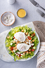 Healthy salad for lunch with fresh vegetables, chickpeas and feta topped with poached eggs