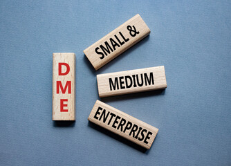 DME - Small and Medium Enterprise symbol. Concept word DME on wooden blocks. Businessman hand. Beautiful grey background. Business and DME concept. Copy space.