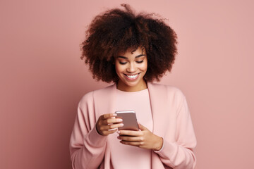 Cheerful shopper in pink t-shirt pays for fashion goods with credit card while ordering online. Stylish model shopping online on mobile phone while standing in studio