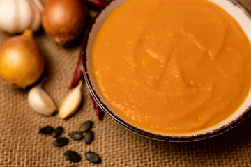 A bowl of pumpkin soup with vegetables on the table.Rustic autumn food.Diet soup