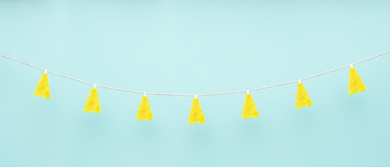 A minimalistic garland of bright yellow tassels against a pastel blue backdrop - obrazy, fototapety, plakaty