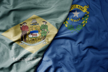 big waving colorful national flag of nevada state and flag of delaware state . macro