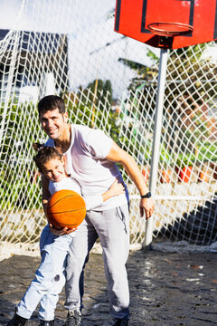 Happy father smiling hugging his daughter with the basketball