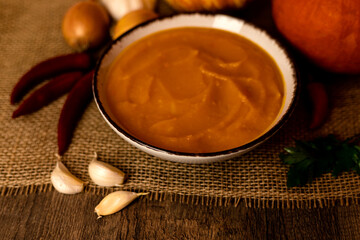 A bowl of pumpkin soup with vegetables on the table.Rustic autumn food.Diet soup