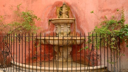 Fountain on rouge wall in Seville, Andalusia, Spain