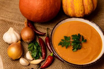 A bowl of pumpkin soup with vegetables on the table.Rustic autumn food.Diet soup