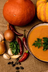 A bowl of pumpkin soup with vegetables on the table.Rustic autumn food.Diet soup