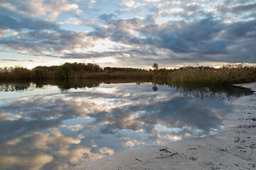 Reflection of the clouded sky in the lake of the Geestmerambacht recreational area. During sunset, the typically Dutch clouds drifted by, reflecting in the tranquil water. Double enjoyment!