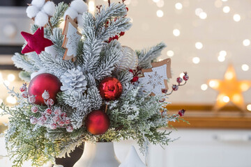 A spruce bouquet with red berries, toys, cotton on a white kitchen table against a beautiful...