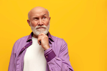 puzzled old bald grandfather in purple shirt with raised eyebrow plans and thinks on yellow...