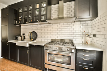 a kitchen with black cabinets and white subway tiles on the wall behind it is an oven, dishwasher...