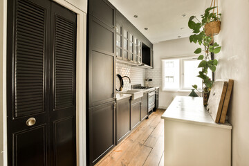 a kitchen with black shutters on the door and wood flooring in the room below is a plant hanging...