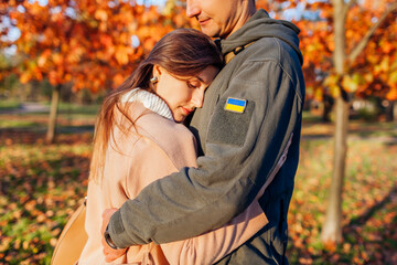 Mental health during war. Woman hugging husband in ukrainian military uniform with flag chevron....