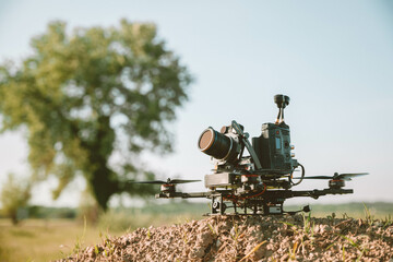 Pro-grade quadcopter with camera, staged in rural setting.