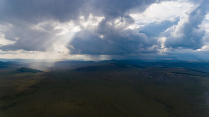 Fototapeta na wymiar Sunrays piercing through clouds over Mongolian plains.
