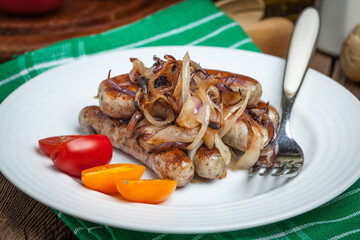 Fried Fried white sausages with onion on the plate.white sausages in a cast iron skillet.