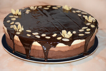 Homemade triple chocolate mousse cake with chocolate mirror glaze and almond flakes
