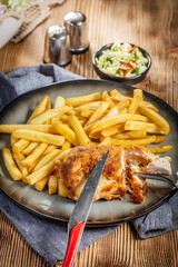 Fried chicken breast stuffed with bacon and cheese served with chips and salad.