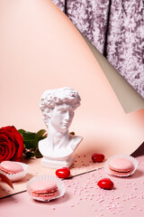 Valentine vertical card with an artificial statue of David with a roses and hearts on a pink background. Creative modern greeting card with copy space for text