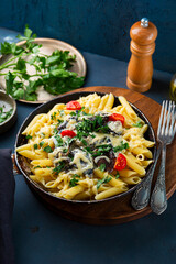 Penne pasta with mushroom sauce in a frying pan on the table, vegetarian comfort food vertical photo