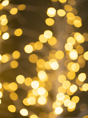 Christmas golden glowing background. Golden festive abstract shiny defocused background with flashing garlands. Tinsel blurred gold bokeh on a black background.