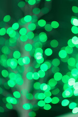 The concept of festive illumination and decoration is a Christmas garland with green bokeh lights