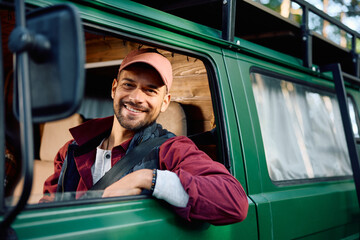 Happy man driving camper van and looking at camera.