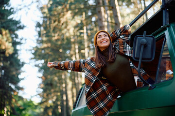 Carefree woman enjoying in journey while traveling through nature with camper van.