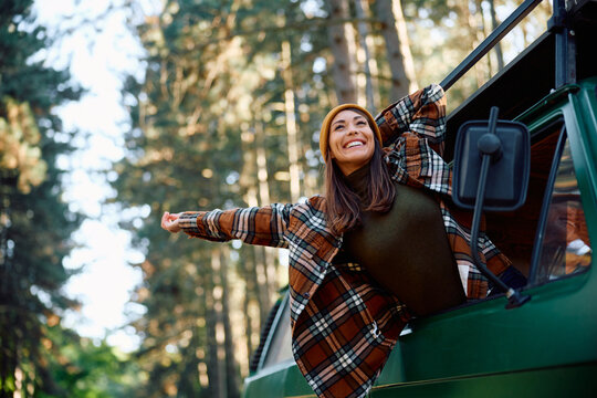 Carefree woman enjoying in journey while traveling through nature with camper van.