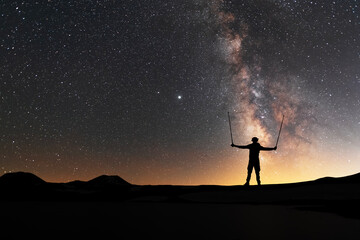 Obraz na płótnie Canvas Silhouette of a hiker standing on the hill, on the milky way galaxy background. Cosmos wallpaper. 