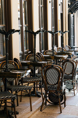 Outdoor empty closed coffee and restaurant terrace with tables, vintage white and black chairs. Cafe terrace on the pedestrian street in Europe. Upturned tables. End of tourist season