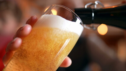 Filling Glass with Beer at Restaurant, traditional golden pour, close-up face holding refreshing drink