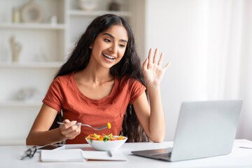 Cheerful millennial indian woman have lunch break at home office