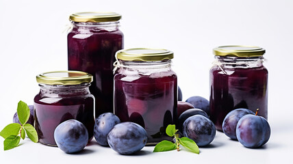 Plums and jam on a white background. Glass jar of plum compote and fresh plums on a white table. Homemade plum jam in a glass jar on a white background. Canned fruits.