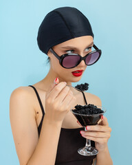 Beautiful Fashion Model woman eating black caviar. Fashion female with spoon of black Caviar