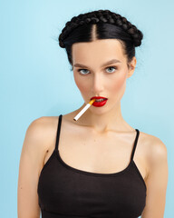 serious young brunette woman on blue background smoking looking at camera