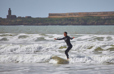 A young female surfer gracefully rides the waves on her board along the shores of Essaouira, Morocco