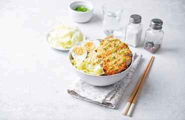 Ramen noodles with meat schnitzel slices, peking cabbage, eggs and scallions in a bowl