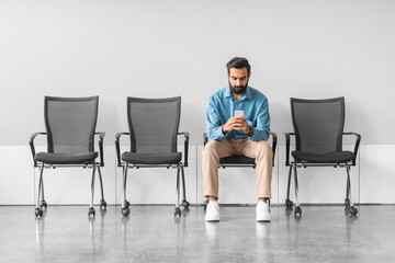 Fototapeta premium Indian man checking phone while waiting for interview