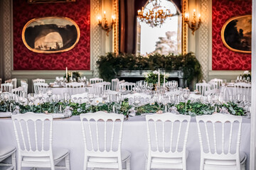 banquet hall with white chairs, white tablecloths and red walls