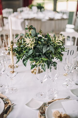 The wedding festive table is decorated with floral arrangements, glasses, plates and cutlery, the table is covered with a beautiful tablecloth