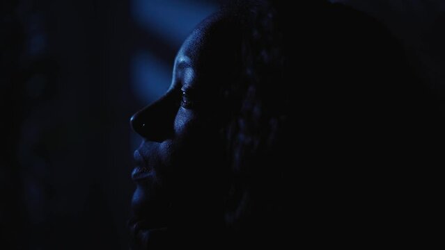 Close-up face young American black woman feelings loneliness and depression alone in room at home in dark, female pensive sad. Girl has mental problems and insomnia. Concept of anxiety in solitude. 