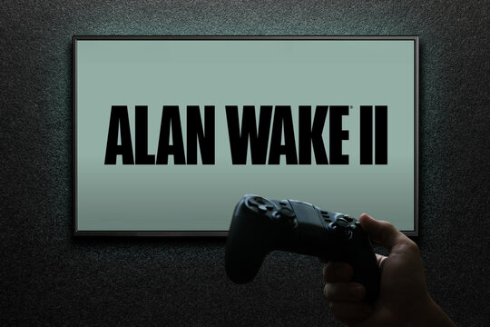 Alan Wake 2 game on TV screen with gamepad in hand on black textured wall with light. Astana, Kazakhstan - November 13, 2023.