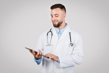 Man doctor using tablet, focused on screen