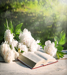 Bible and a bouquet of peonies on a table in the garden