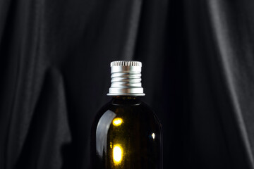Brown glass bottle for cosmetics on a black background. Mockup container for cream..